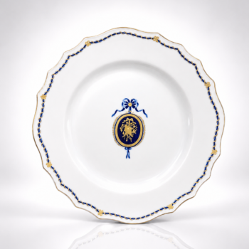 Porcelaine de Tournai - Assiette au médaillon Louis XVI bleu et or à attributs.